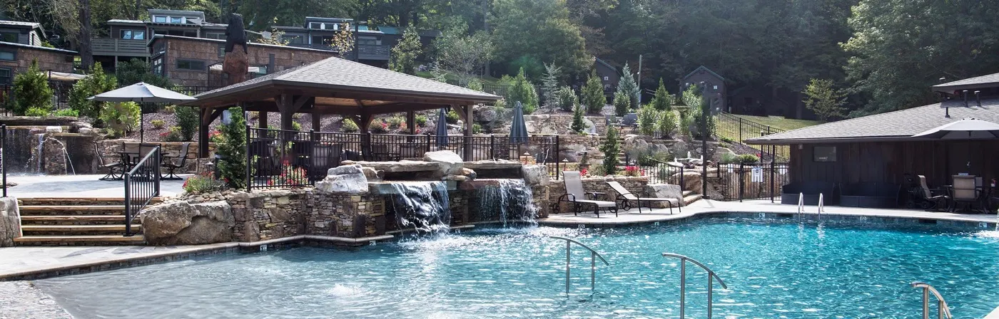 Pool with a stacked-stone waterfall, a pavilion and lounge chairs, built by Teaster's Natural Creations