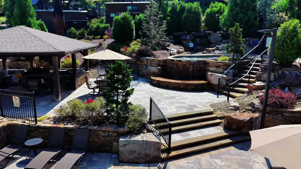 Stone patio with a raised hot tub, wide stone steps and planted beds, built by Teaster's Natural Creations